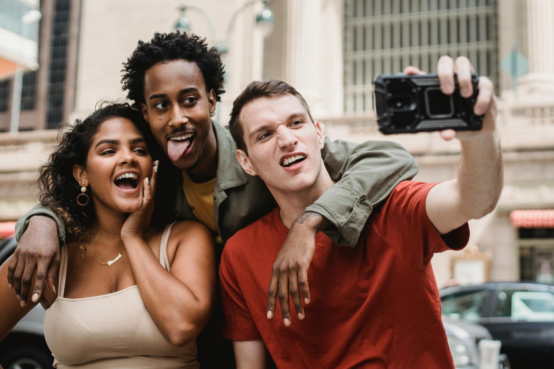 A diverse group of friends enjoying a light-hearted selfie in the city street, showcasing friendship and fun.